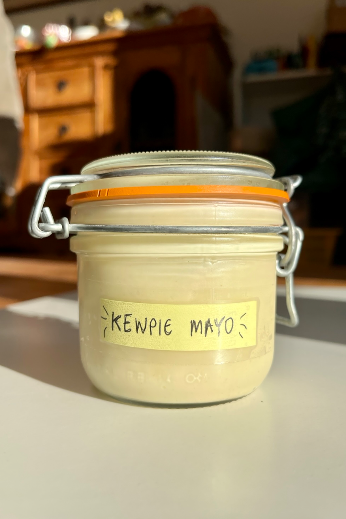 Glass jar with a label saying kewpie mayo on it.