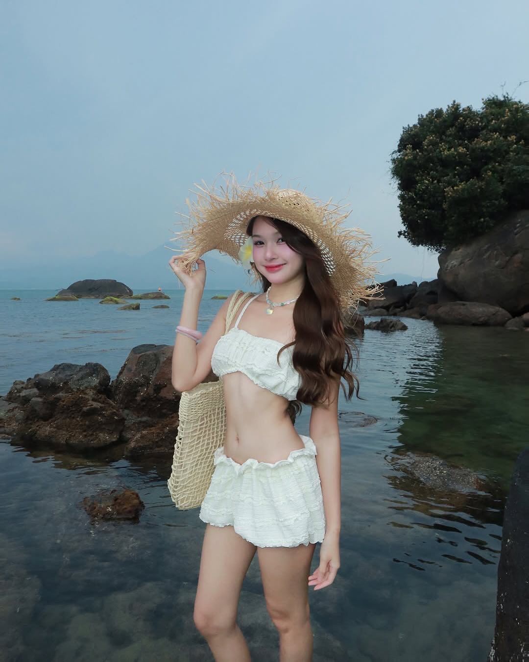 Tay vuốt tóc nhẹ khi đứng trước biển