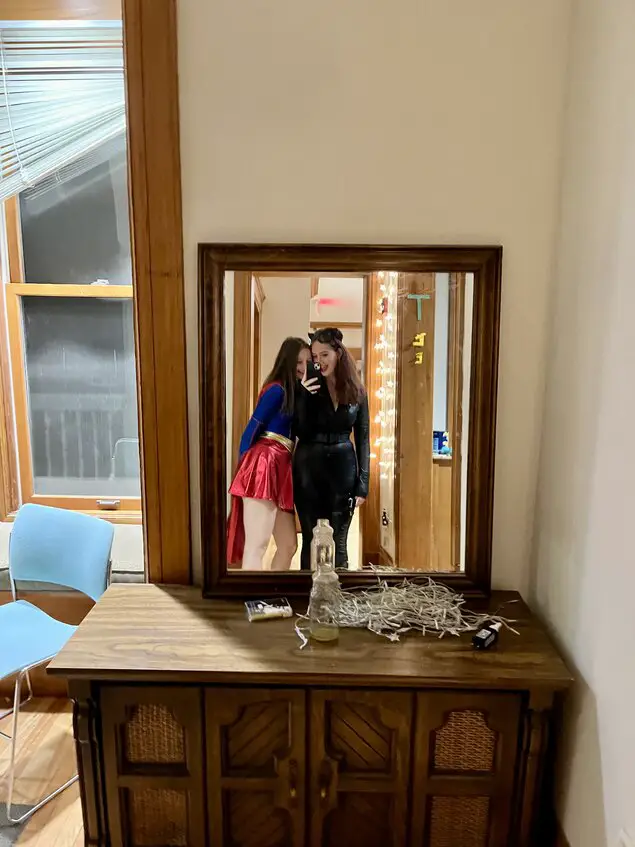 Mirror picture of a girl in a Batman costume and a Superwoman costume