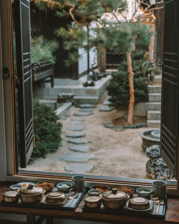 View of traditional Korean breakfast laid out at a window that opens up to hanok courtyard