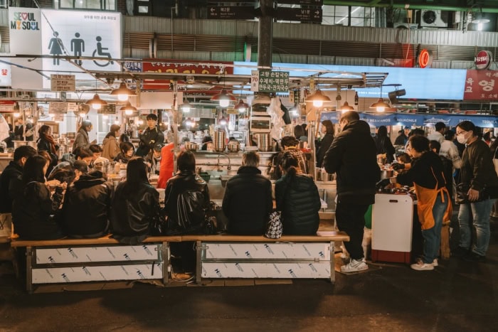 Busy stall in Gwangjang Market in Seoul with patrons getting served food