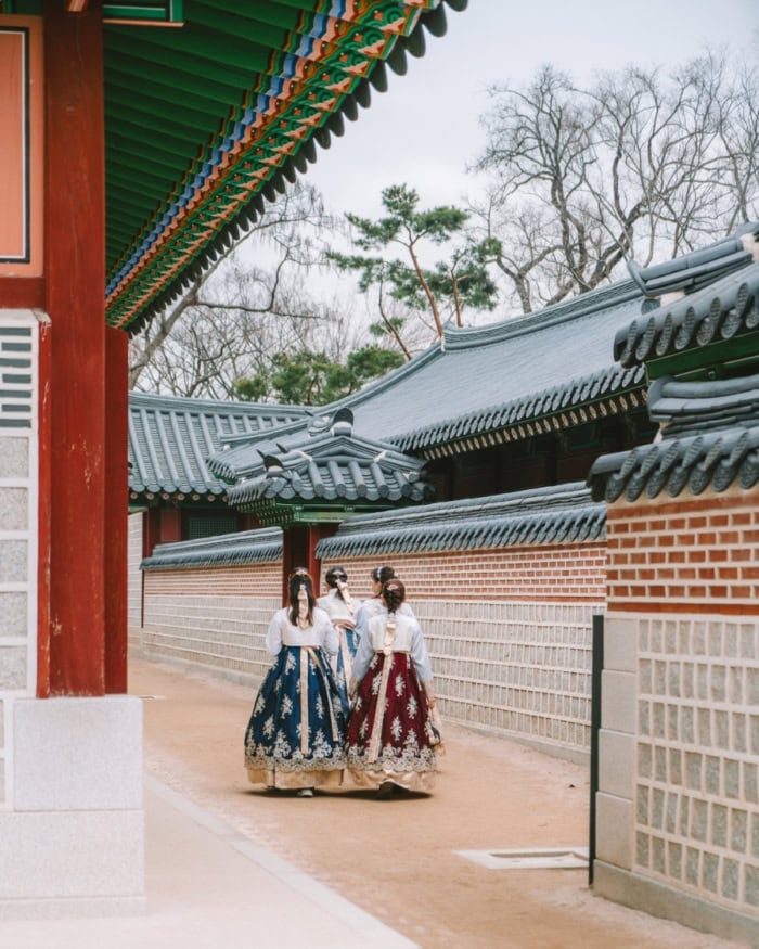 Four women in hanbok dresses standing in Gyeongbukgong Palace courtyard