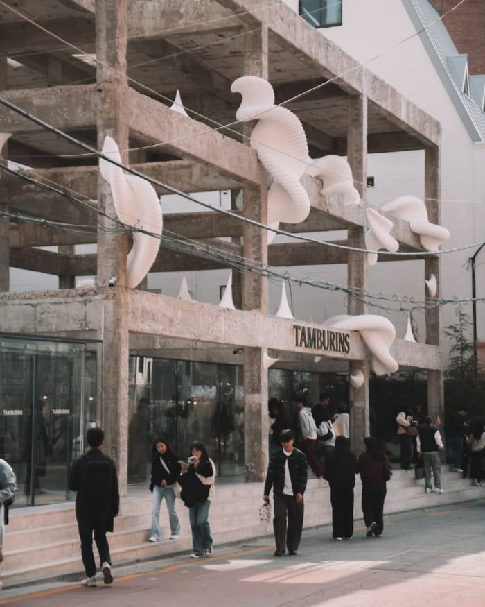 Exterior view of Tamburins in Seoul, a concrete building with white sculptures twisted around the frame