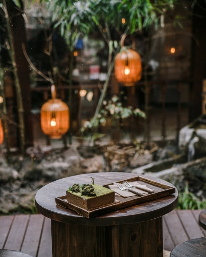 Outdoor café with hanging lanterns and a green sponge cake sitting on a table