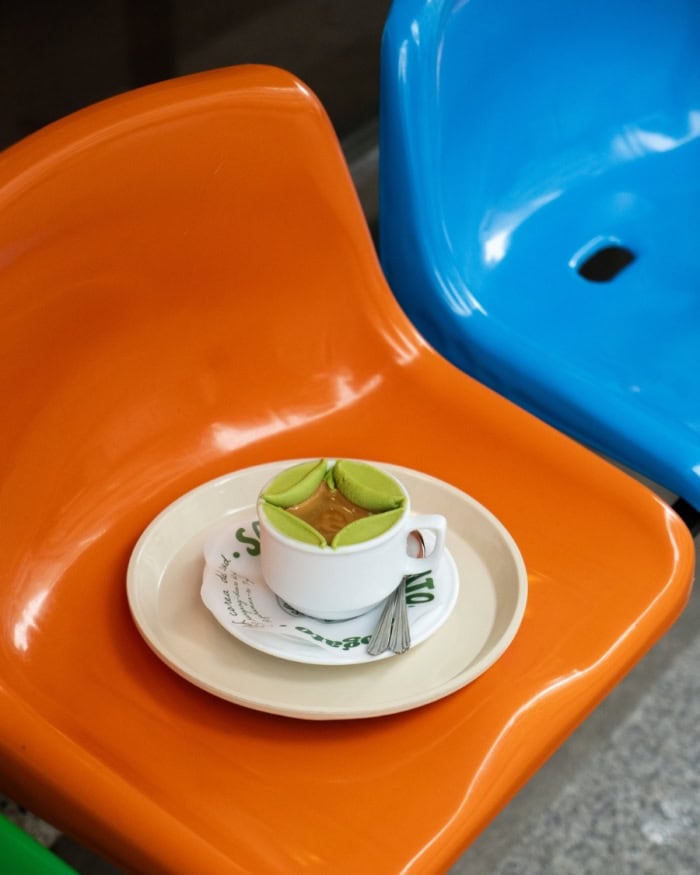 Bright green matcha affogato in a teacup on bright orange and blue plastic chair