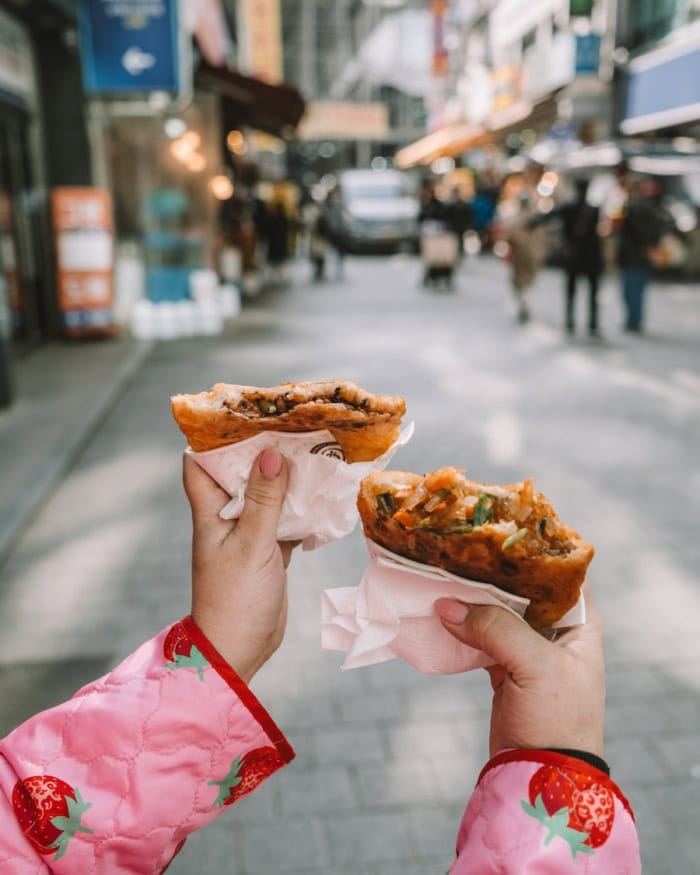 Sweet and savory hotteok fried pancakes behind held up for the camera