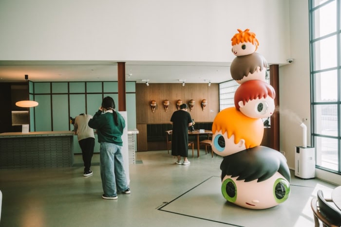 Sculpture of stacked cartoon heads inside an art museum space