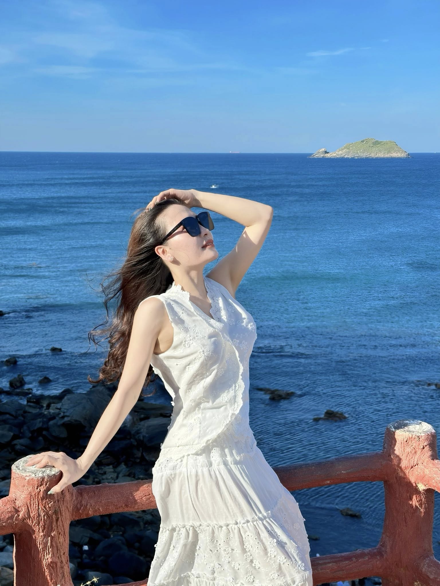 Ngồi trên bờ cát vuốt nhẹ váy tạo dáng dịu dàng