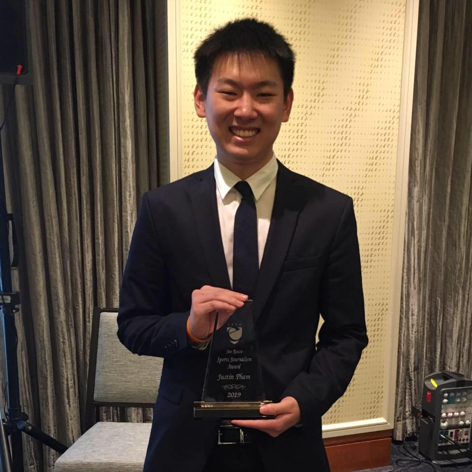 Justin Pham in suit holding award