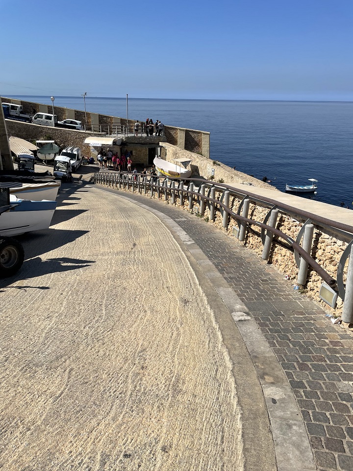 View of sea and stairs with railing down a sloped road for boats