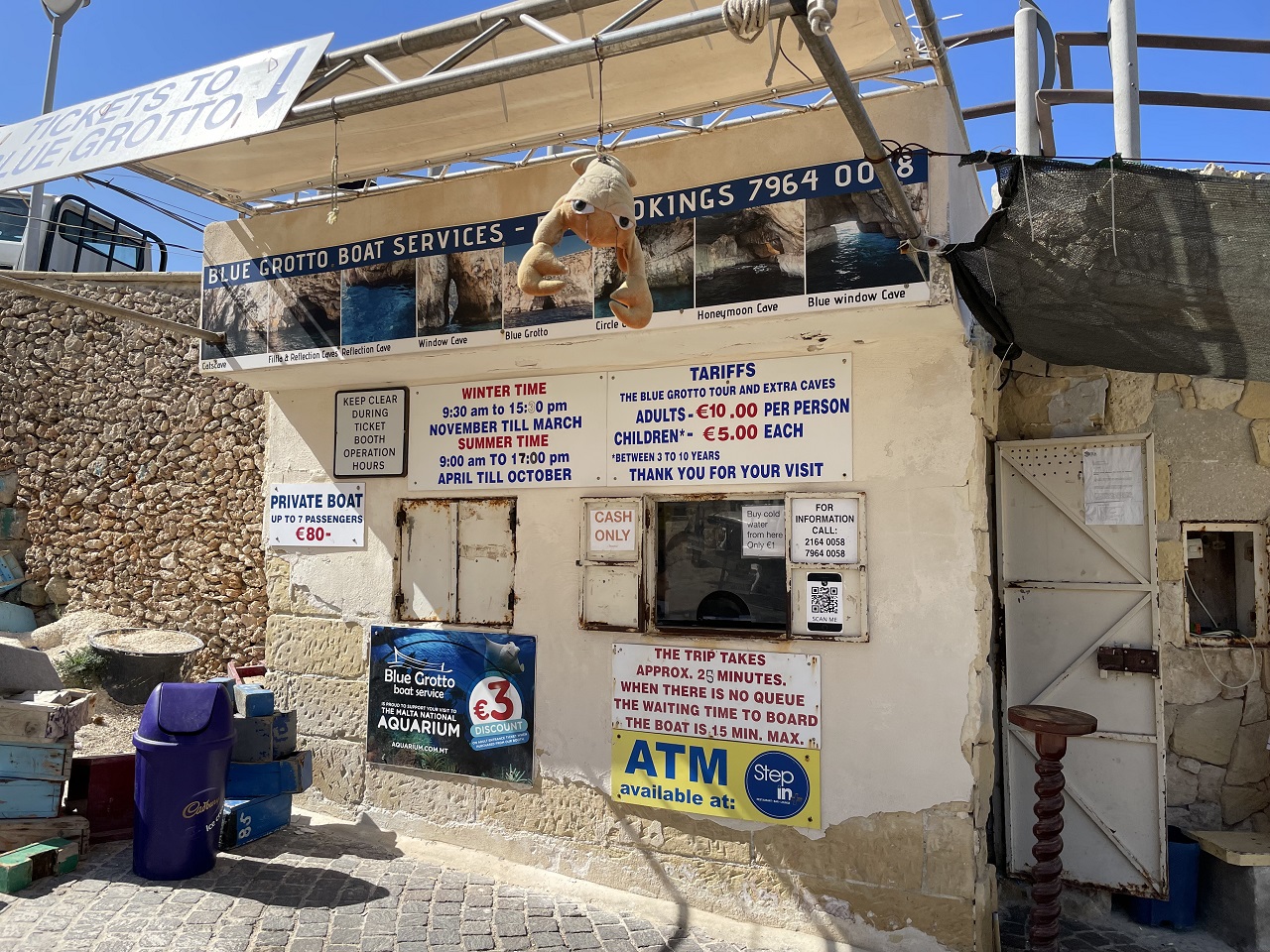 Sandstone ticket booth at the Blue Grotto Malta with various signs and fee listing