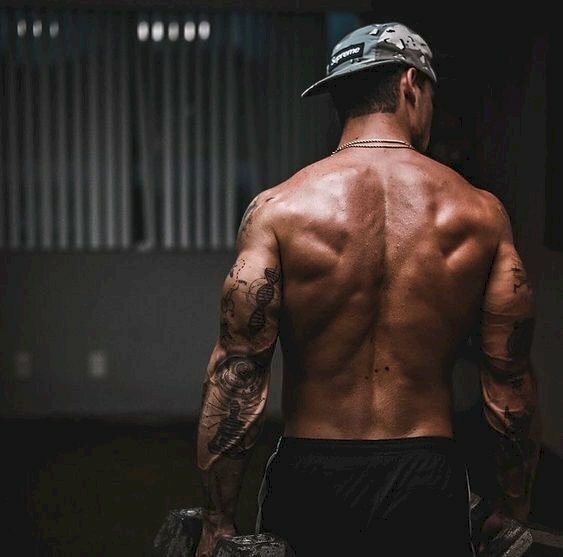 Cách tạo dáng chụp ảnh gym nam giấu mặt quay lưng như đang bước đi, hai tay cầm tạ, với cơ bắp săn chắc và khỏe khoắn