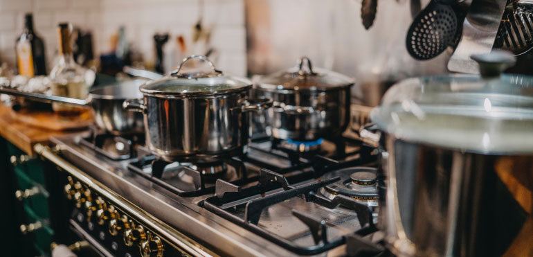 Gas stove with 2 medium sized pots on top.