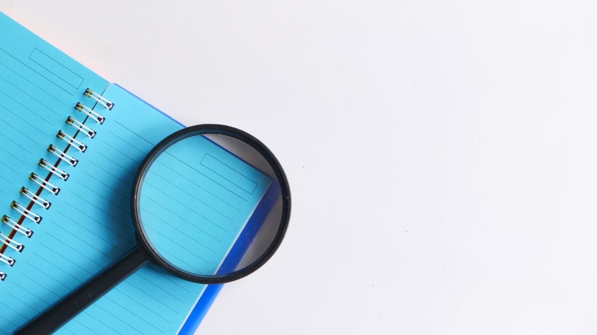 Hình ảnh kính lúp và sổ tay màu xanh dương, tượng trưng cho sự khám phá và tìm hiểu. Phù hợp làm mẫu PowerPoint 20/11.
