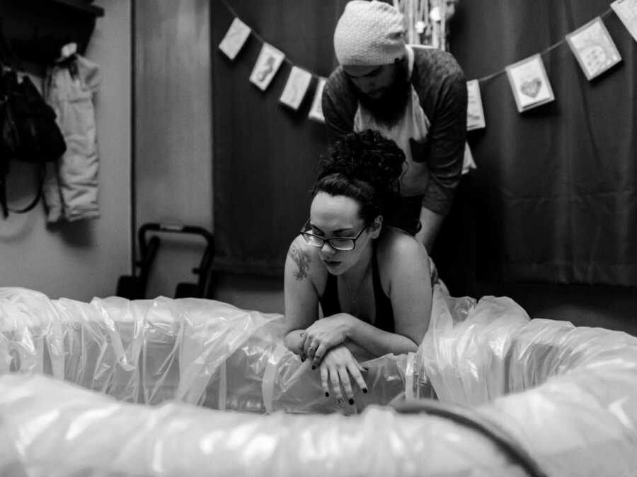 Pregnant woman holding stomach in birthing pool