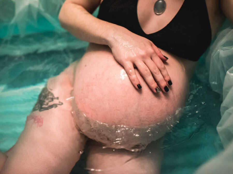 Woman leaning leaning against edge of birthing pool