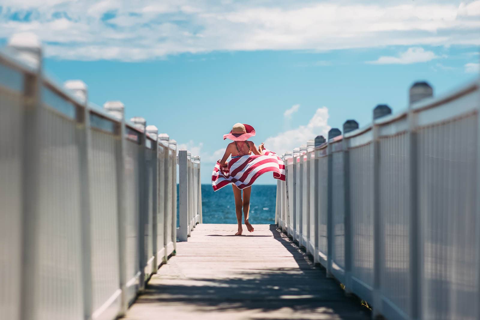 picture of girl walking on the beach with a striped towel by Susan Grimes