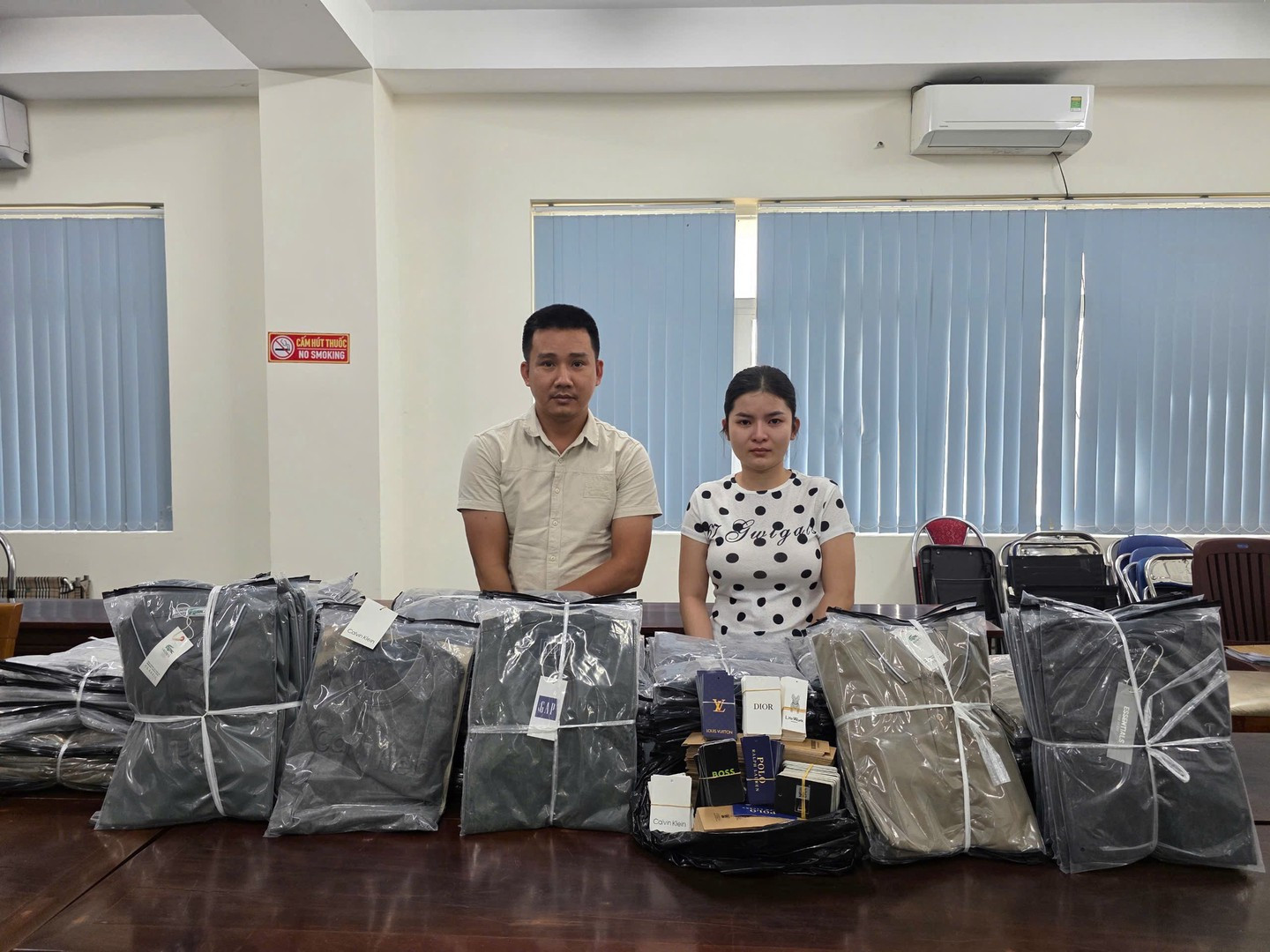 Hai đối tượng Nguyễn Đức Đạo và Phan Thị Hà Ly cùng tang vật áo thun giả nhãn hiệu bị thu giữ.